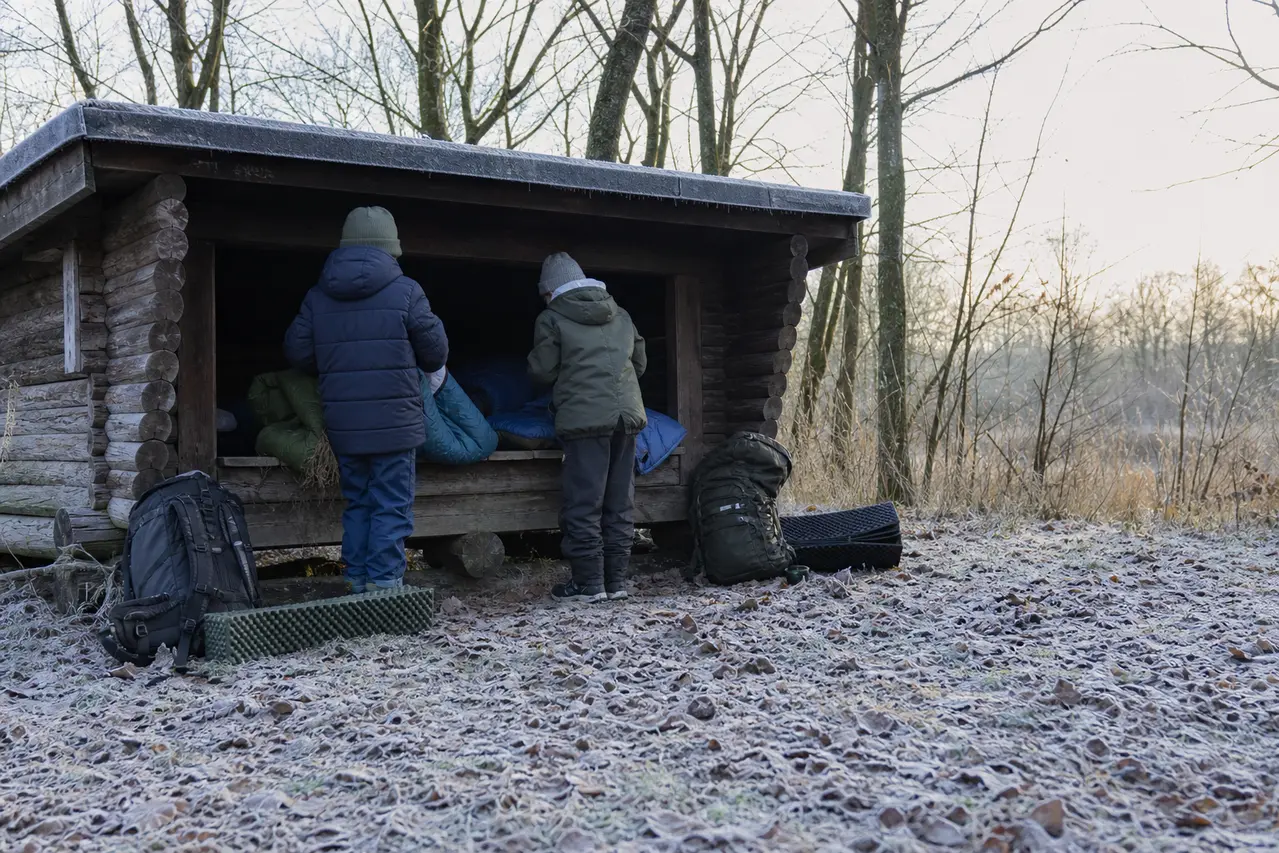 Børn pakker soveposer ved shelter om vinteren