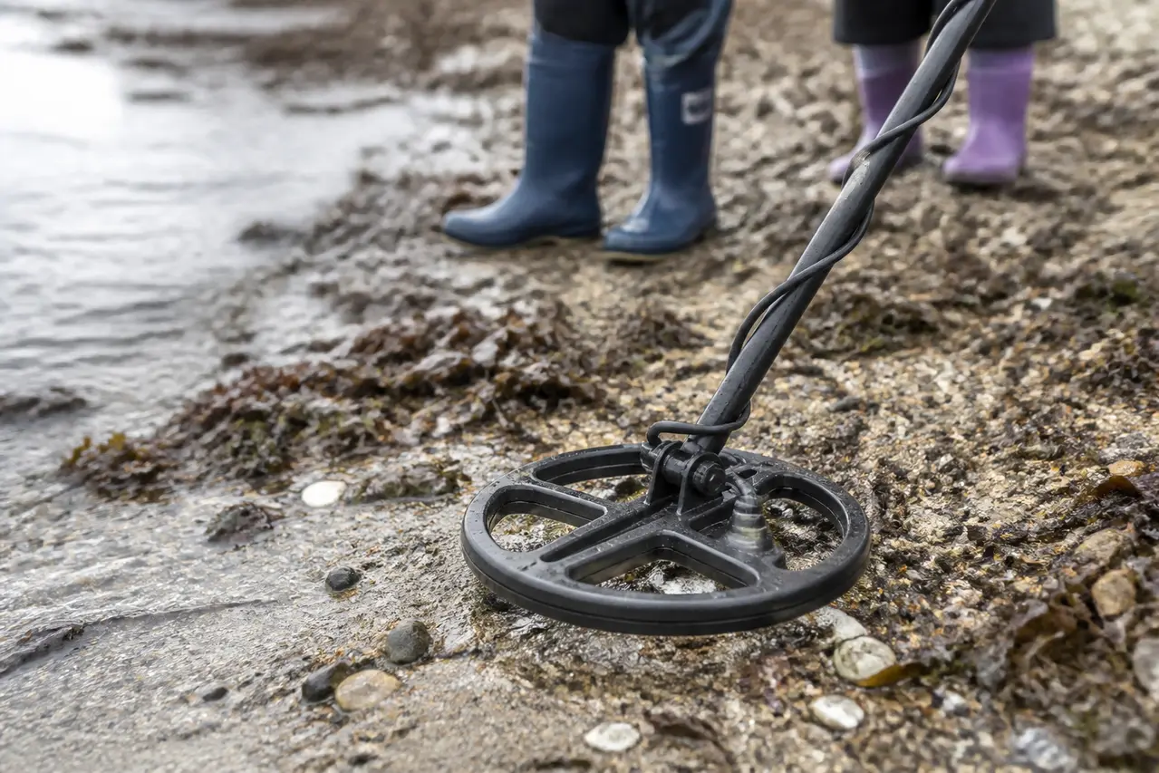 Metaldetektor søger over sand og småsten