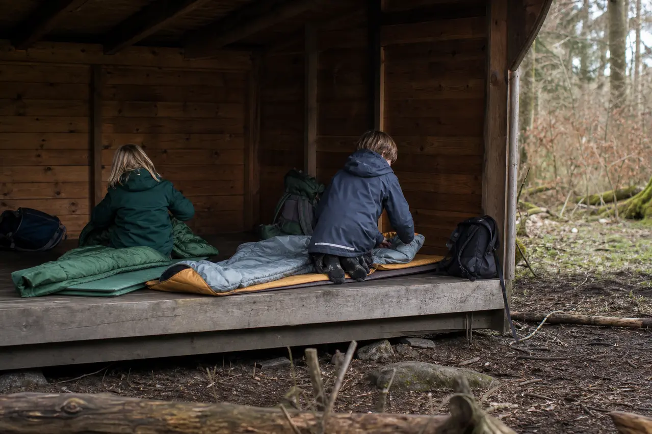 Børn gør soveposer klar i shelter